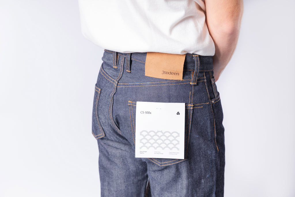 Person wearing blue jeans with a visible brand label on a white background