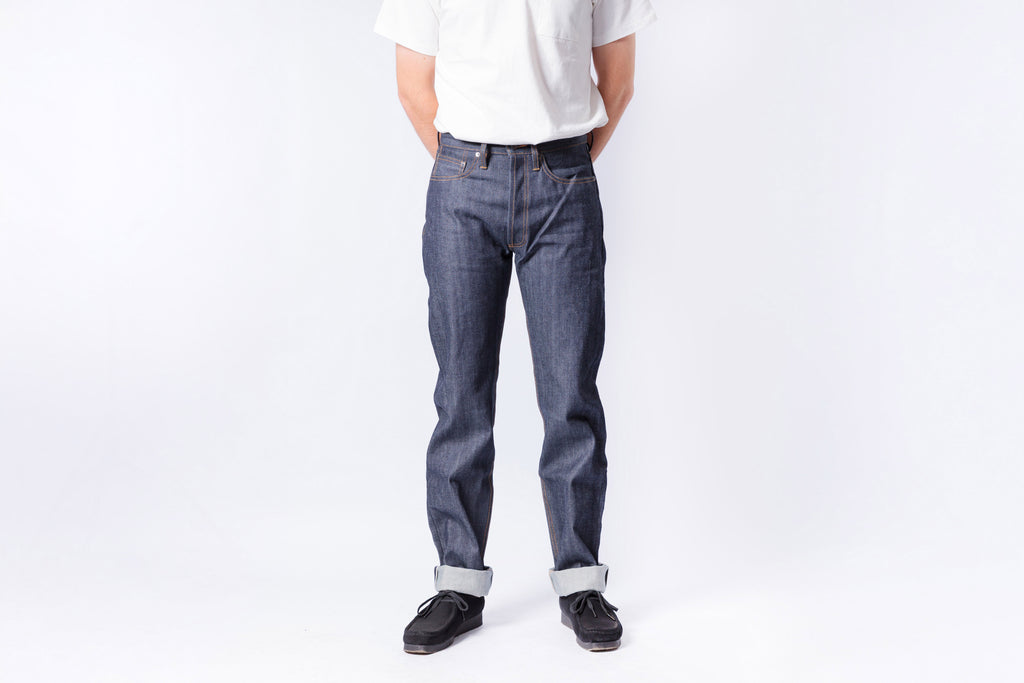 Person wearing blue jeans and a white shirt on a plain background