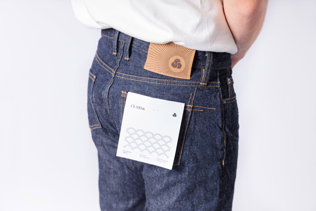 Person wearing blue jeans with a brown leather wallet and white card on a white background