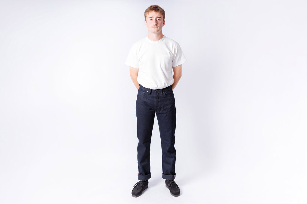 Person wearing a white t-shirt and dark jeans on a white background