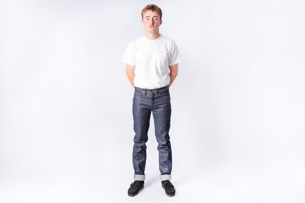 Person wearing a white t-shirt and dark jeans on a white background