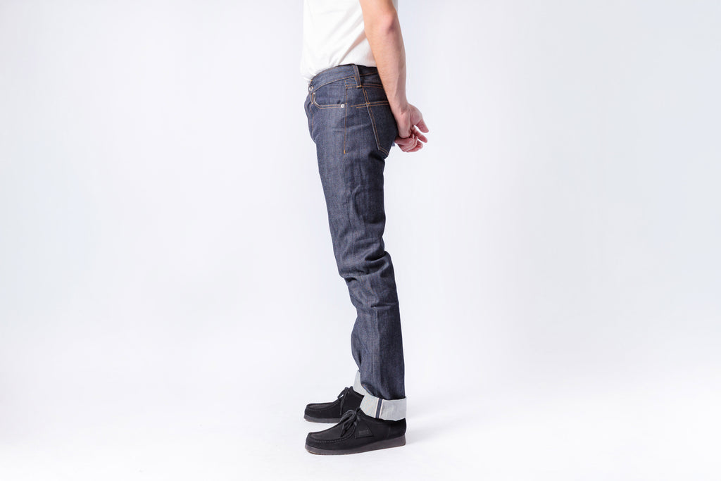 Person wearing blue jeans and black shoes on a white background