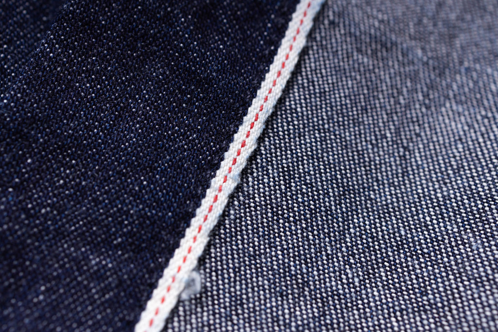 Close-up of denim fabric with a red thread seam