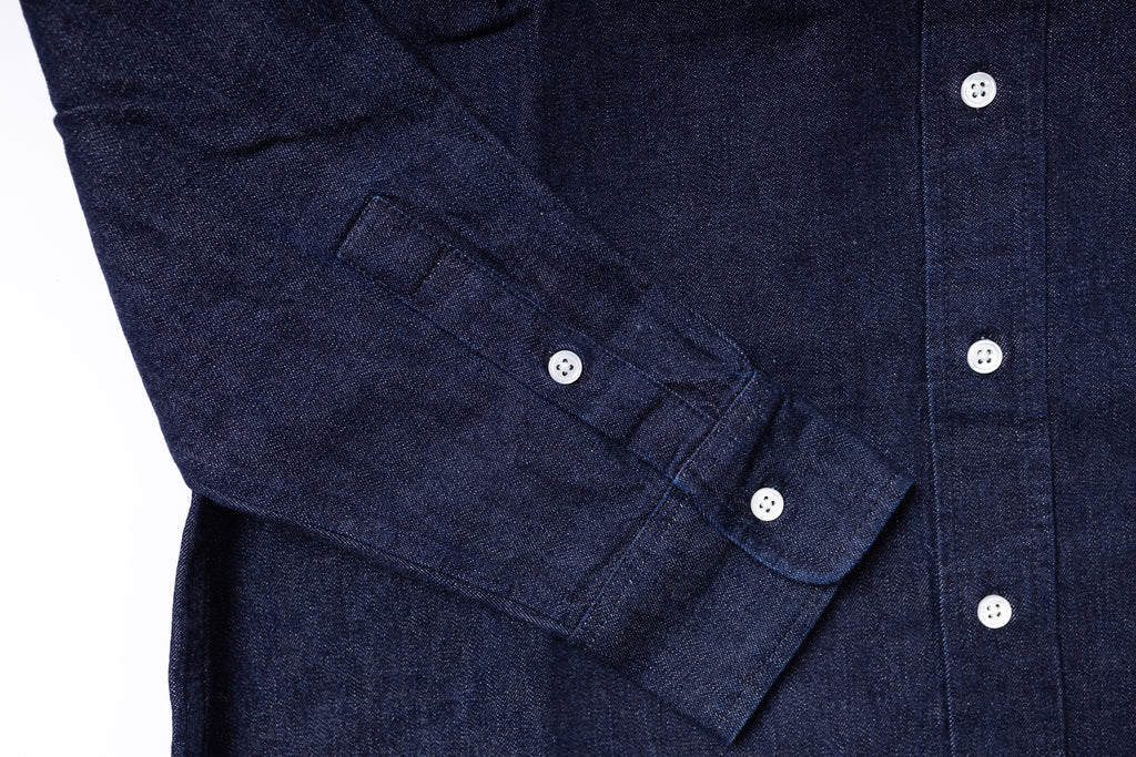 Close-up of a navy blue shirt with rolled-up sleeve cuffs on a white background