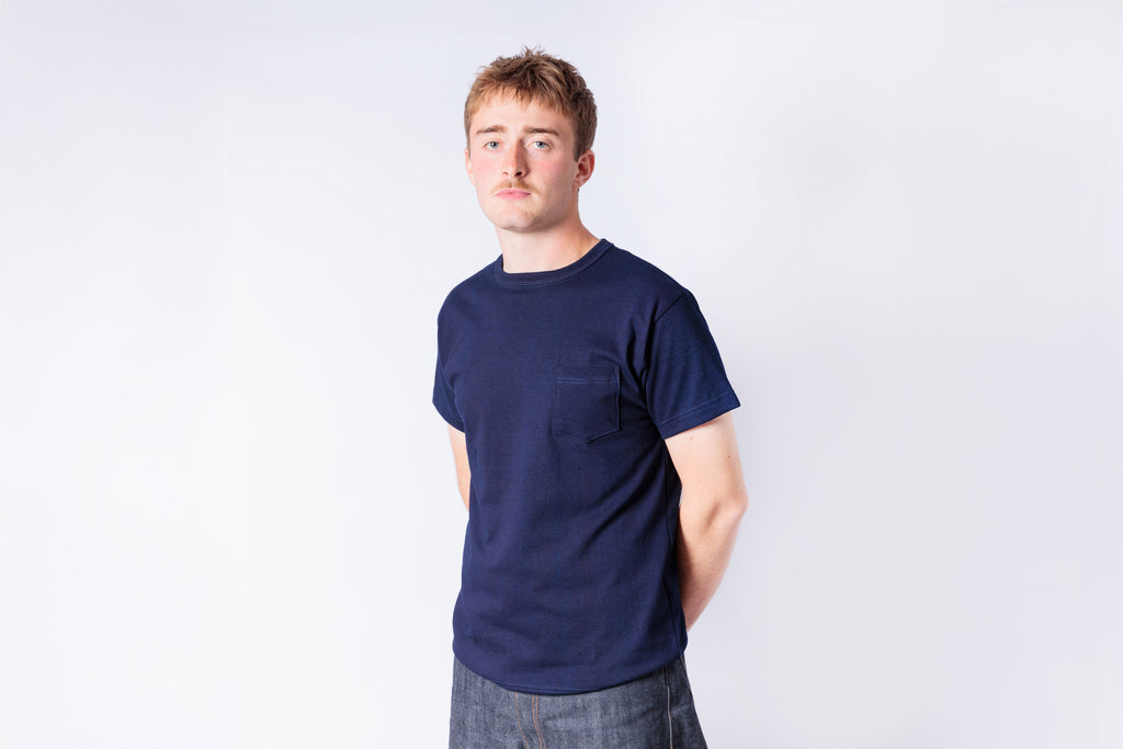 Man wearing a navy blue t-shirt and plaid pants on a white background