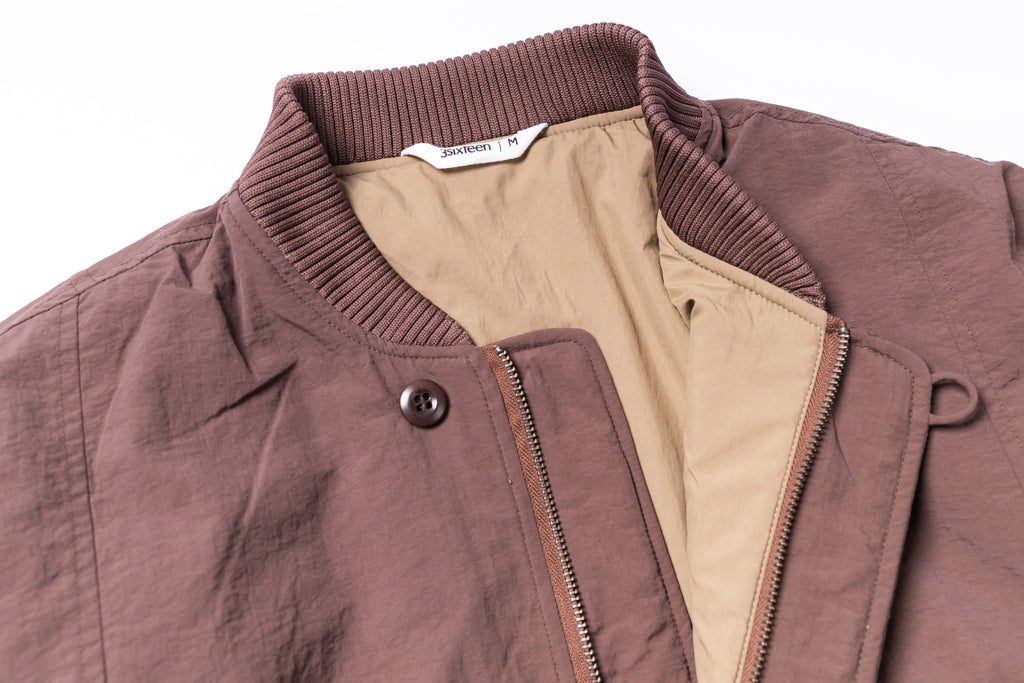 Close-up of a brown jacket with a visible brand label on a white background