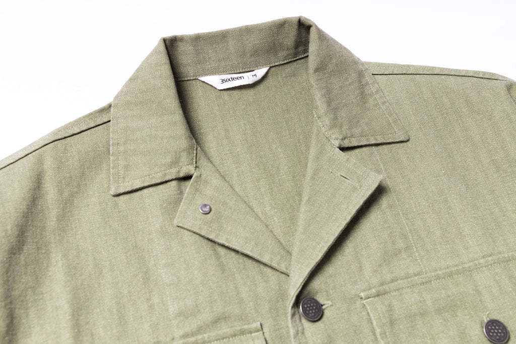 Close-up of a green jacket with a collar and buttons on a white background