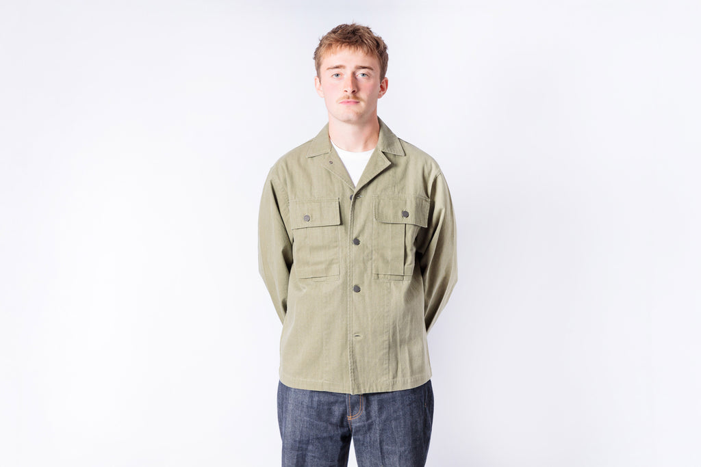 Man wearing a beige jacket and blue jeans on a white background