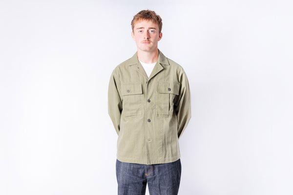 Man wearing a beige jacket and blue jeans on a white background