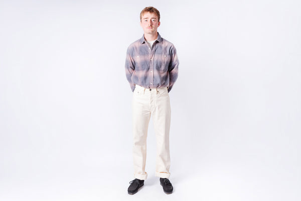 Man wearing a plaid shirt and white pants on a white background