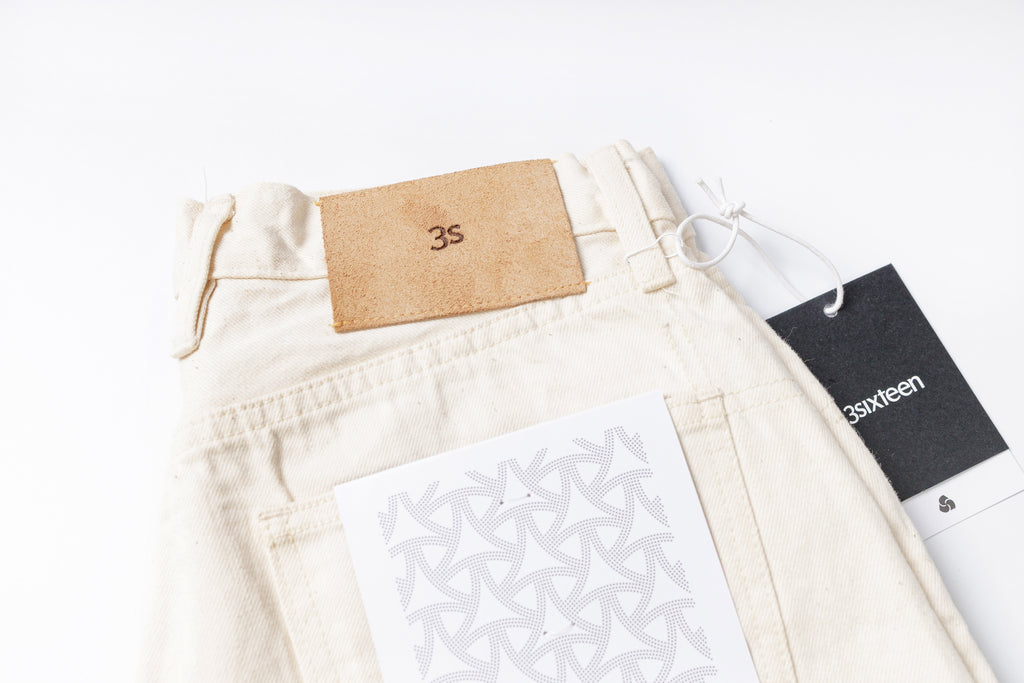 White jeans with a brand tag on a white background