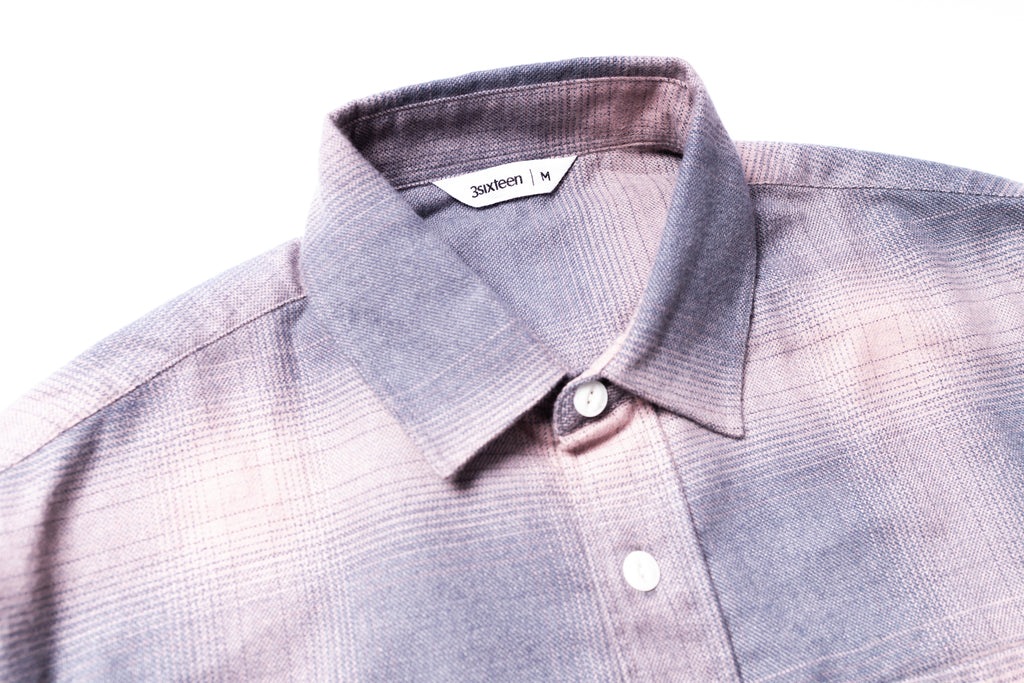 Close-up of a gray checkered shirt with collar and buttons on a white background