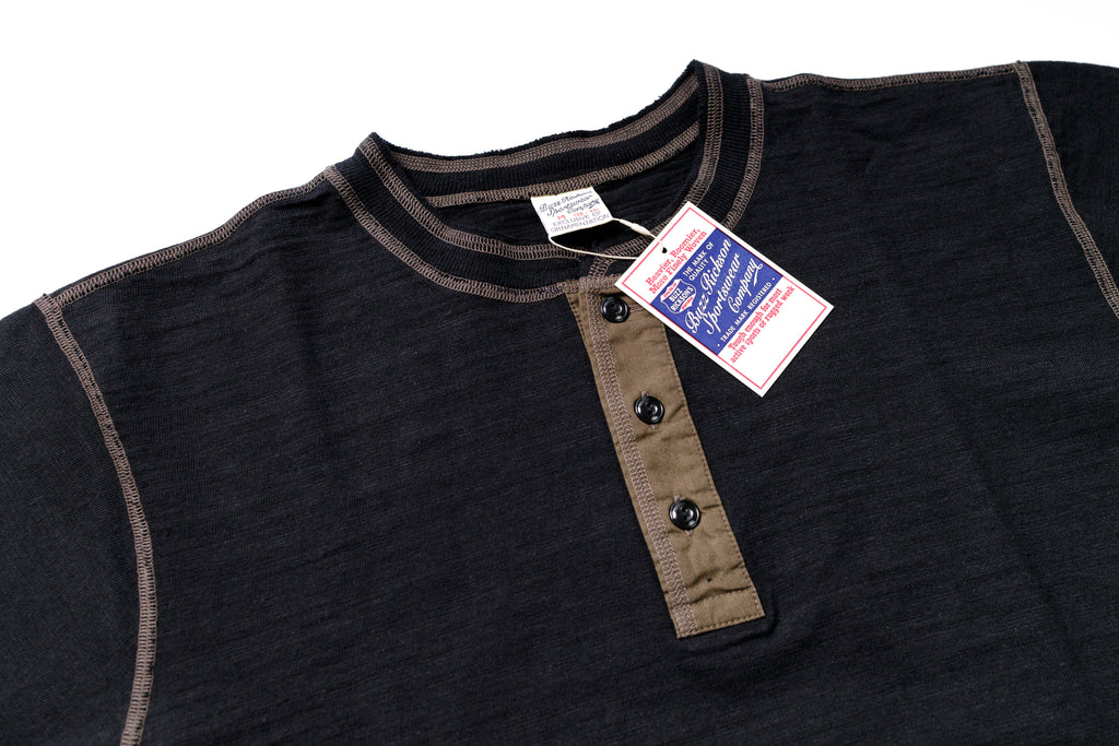 Black shirt with brown trim and buttons, tag attached on a white background