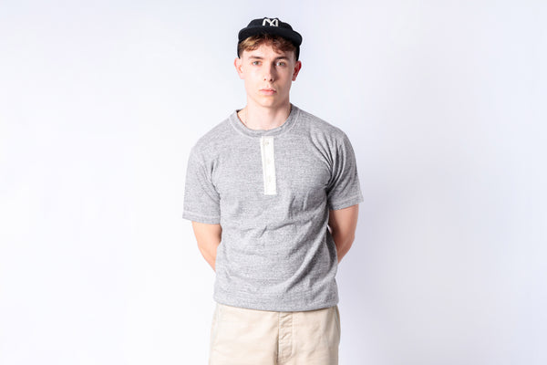Person wearing a gray t-shirt and black cap on a white background