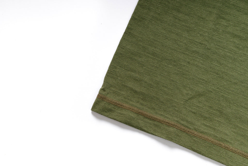 Close-up of a green fabric with brown stitching on a white background