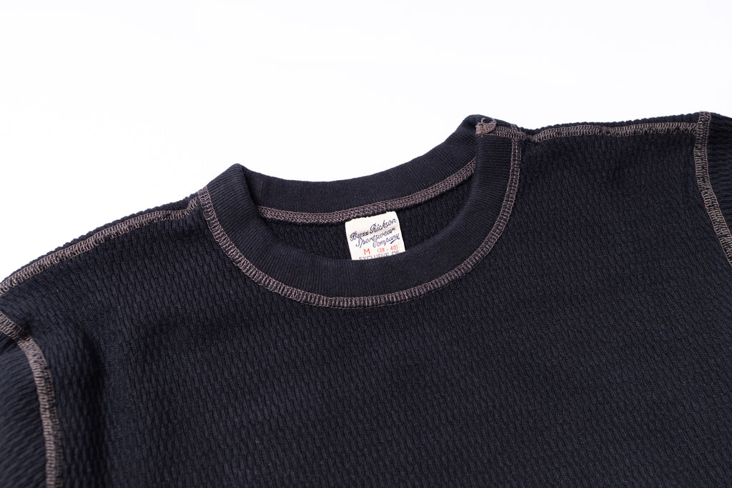 Close-up of a black garment with a brand label on a white background