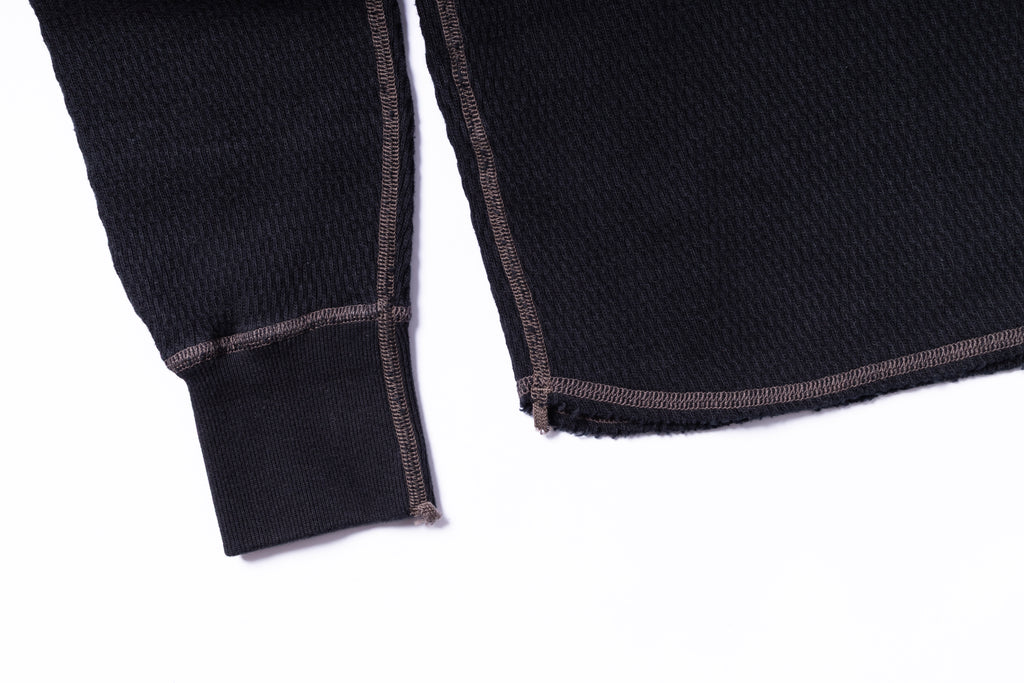 Close-up of a black sweater with brown trim on a white background