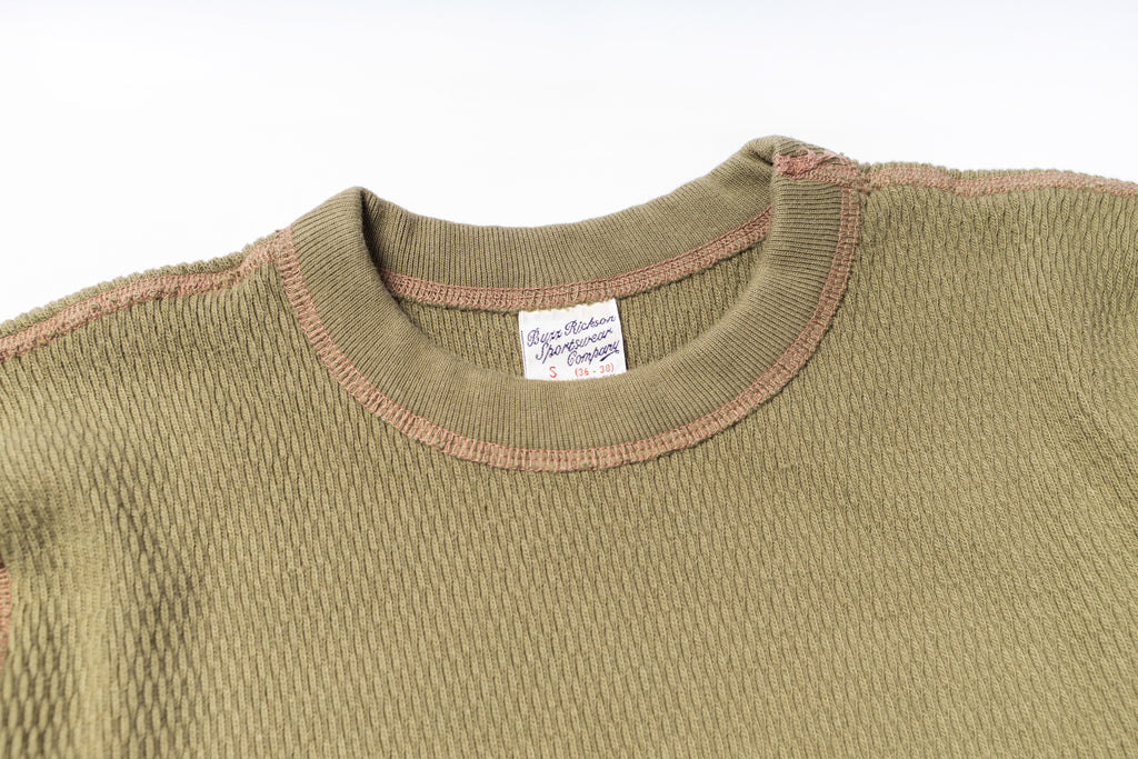 Close-up of a green sweater with a brand label on a white background