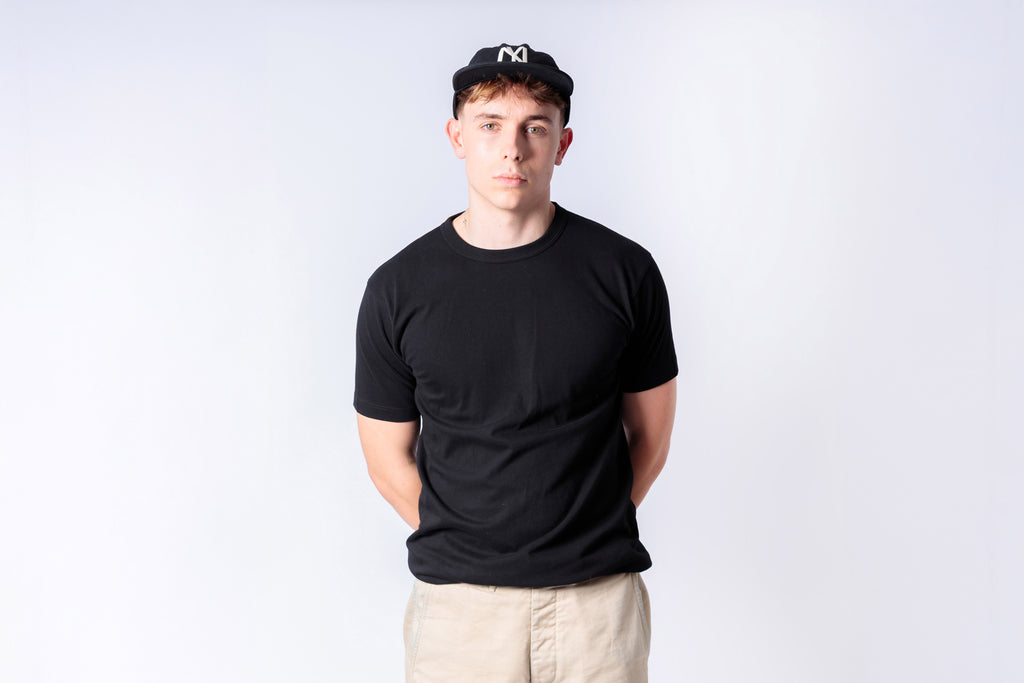 Person wearing a black t-shirt and cap on a white background