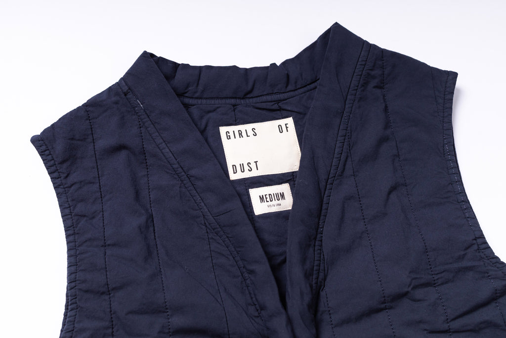 Navy blue sleeveless jacket with a brand label on a white background
