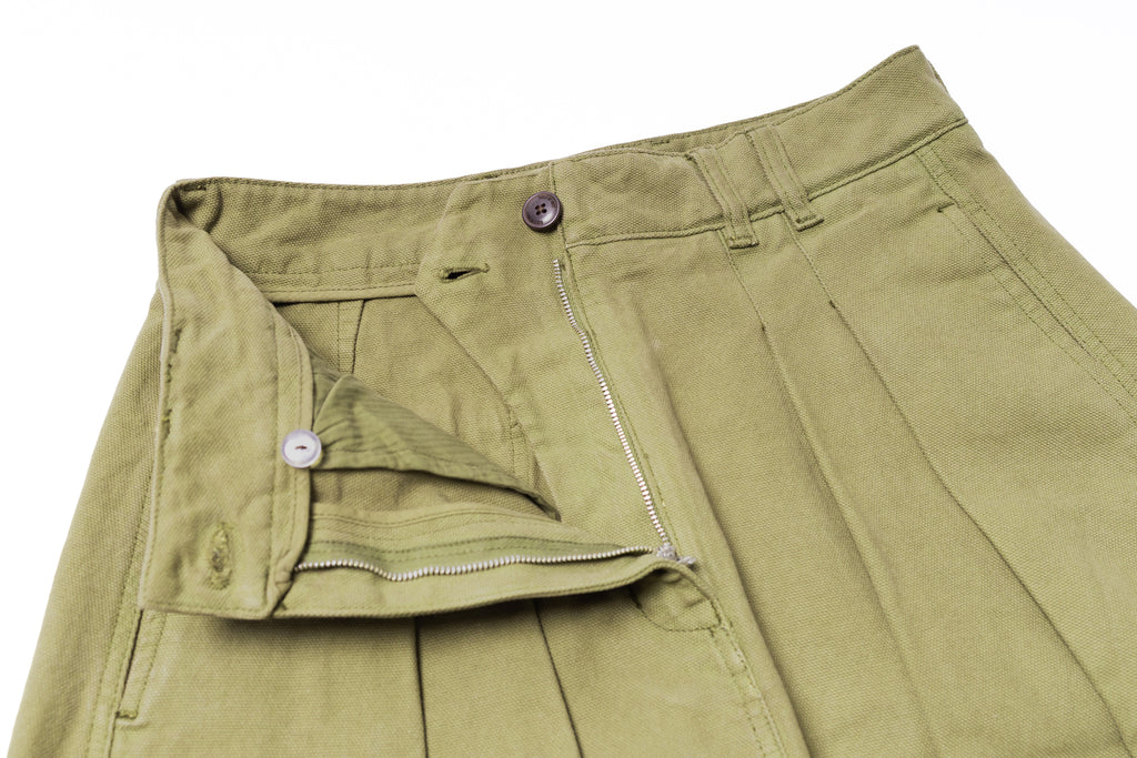 Close-up of green pants with a zipper and button on a white background