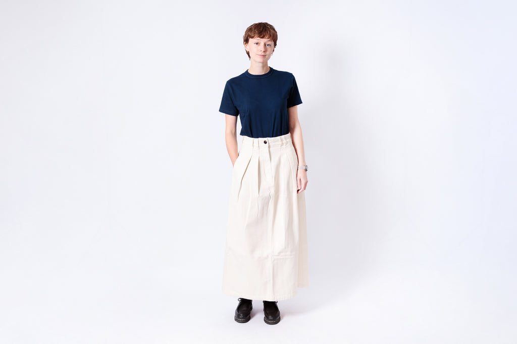 Person wearing a navy shirt and beige skirt on a white background