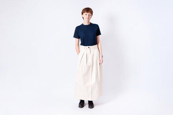 Person wearing a navy shirt and beige skirt on a white background
