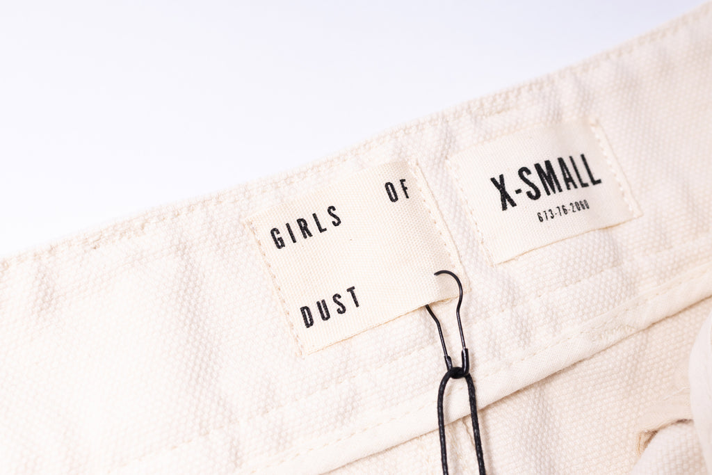 Beige towel with 'Girls of Dust' branding and size label on a white background