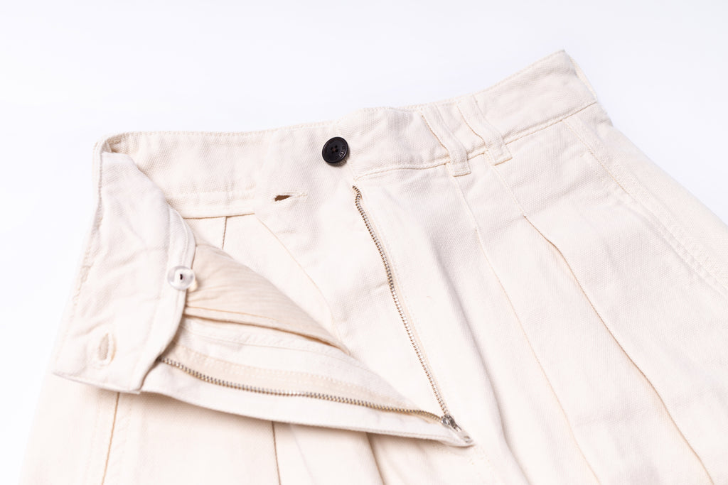 Close-up of beige pants with a button on a white background