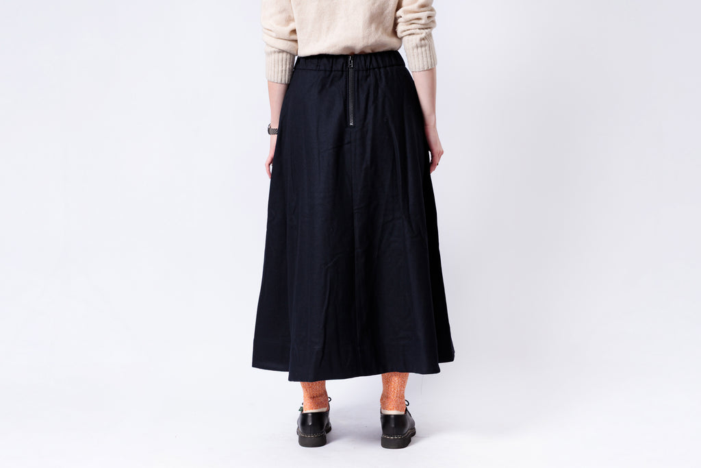 Person wearing a black skirt on a plain background