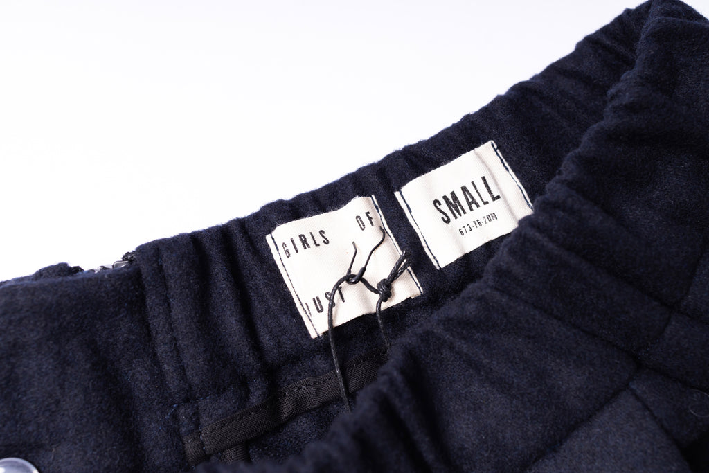 Close-up of dark pants with a label on a white background