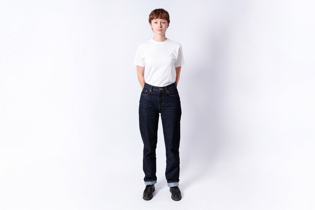 Person wearing a white t-shirt and dark jeans on a white background