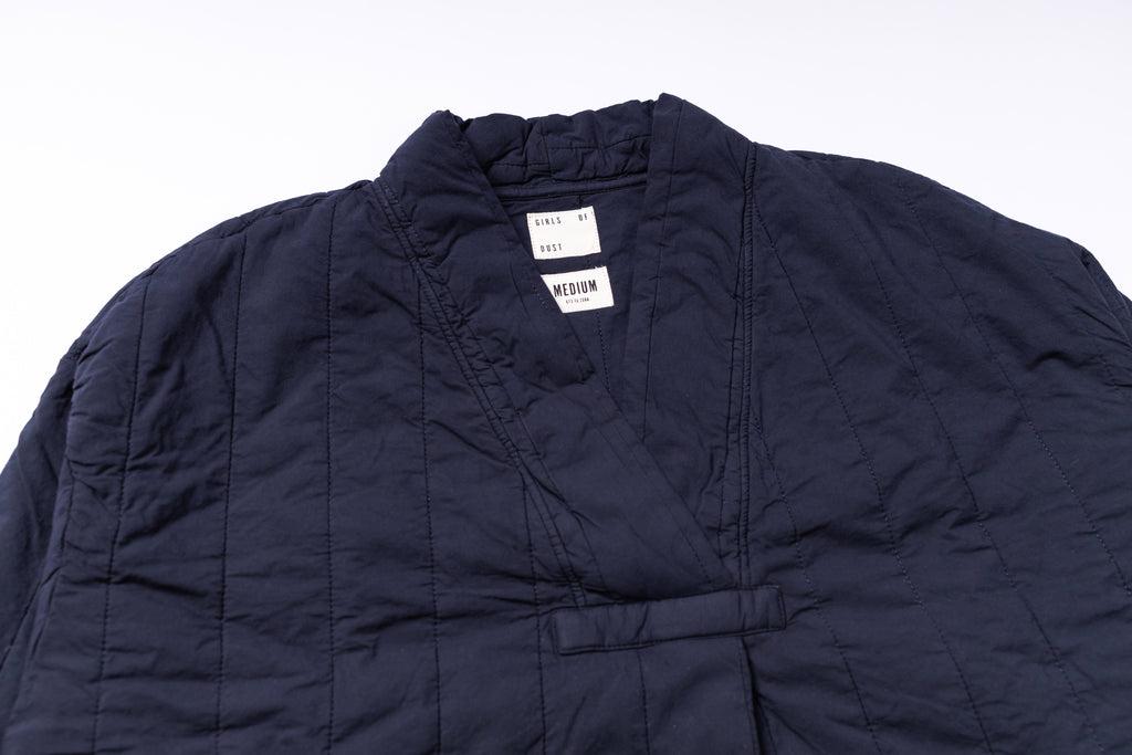 Navy quilted jacket with a brand label on a white background