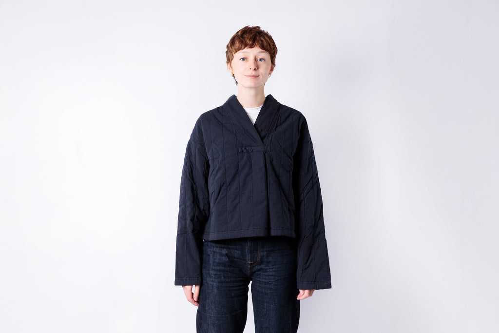 Person wearing a dark jacket and jeans on a white background