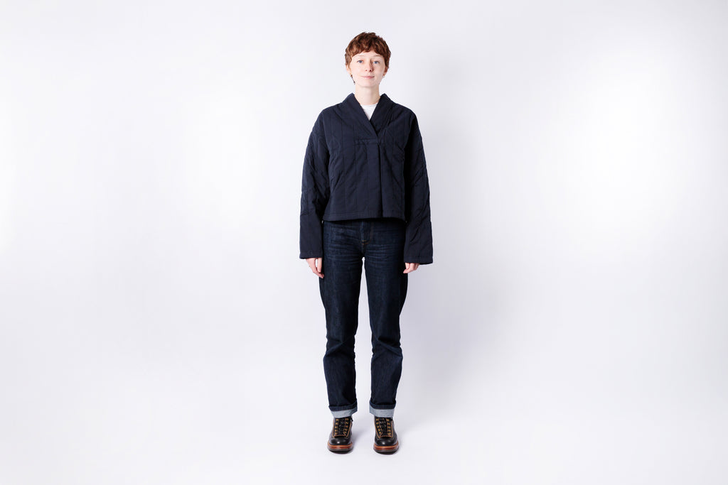 Person wearing a dark jacket and jeans on a white background