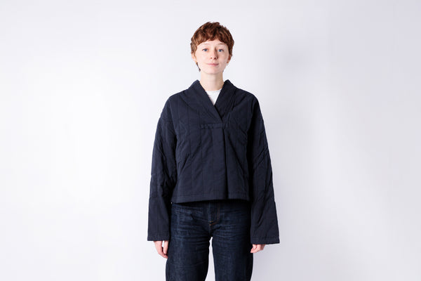 Person wearing a dark jacket and jeans on a white background