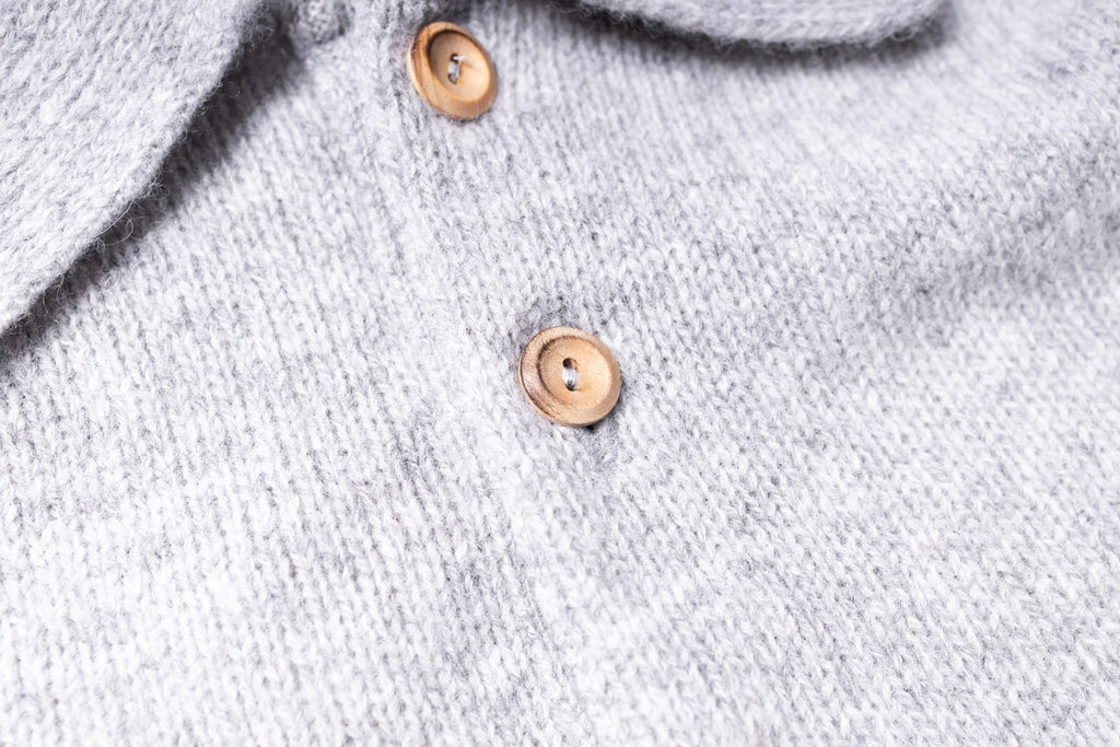 Close-up of a gray knitted sweater with wooden buttons.