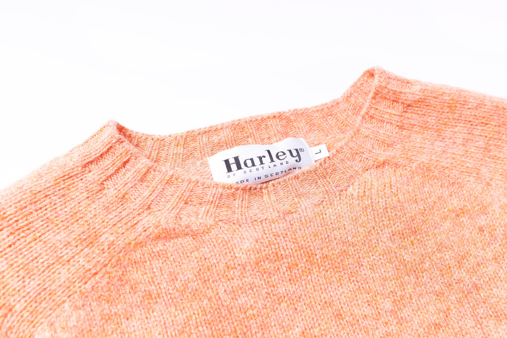 Close-up of an orange sweater with a Harley label on a white background