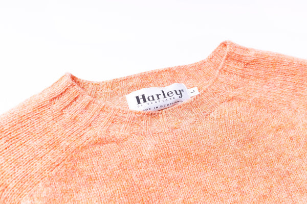 Close-up of an orange sweater with a Harley label on a white background