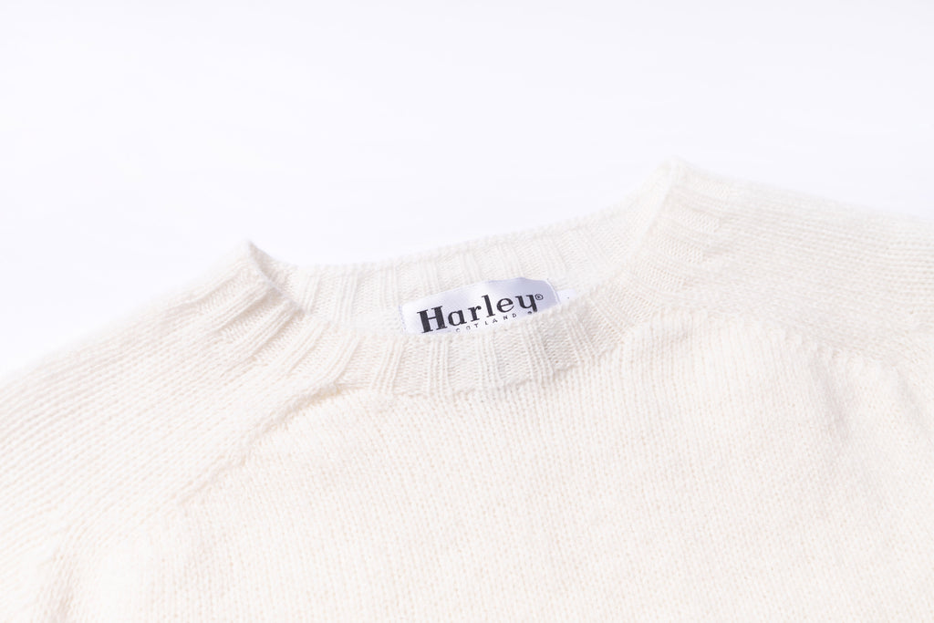 Close-up of a white sweater with a 'Harley' label on a white background
