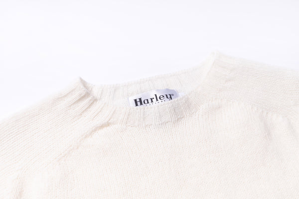 Close-up of a white sweater with a 'Harley' label on a white background