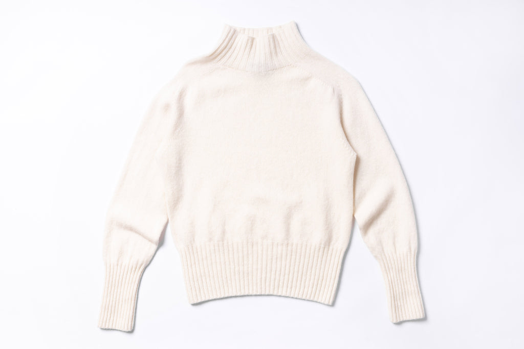 White turtleneck sweater on a light gray background