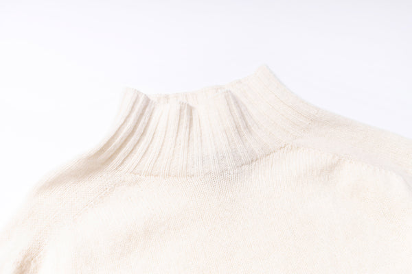 Close-up of a beige sweater with a ribbed texture on a white background