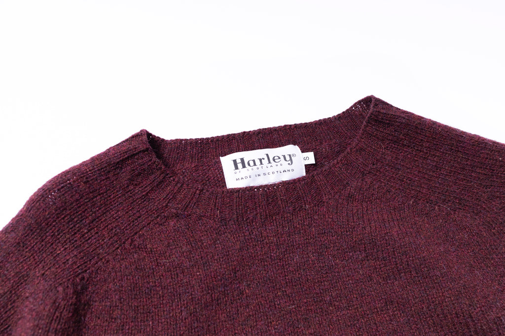 Close-up of a maroon sweater with a Harley label on a white background