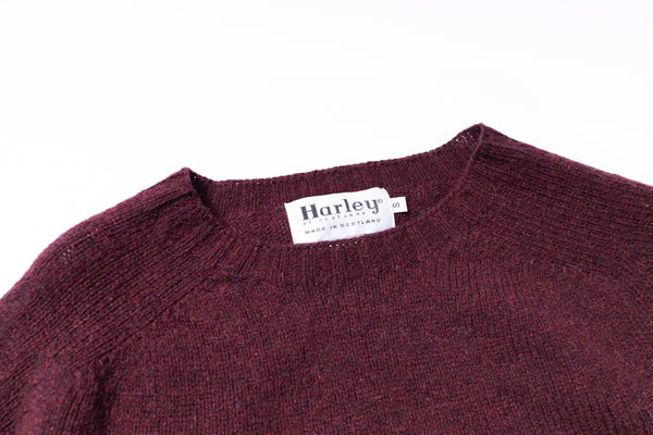 Close-up of a maroon sweater with a Harley label on a white background