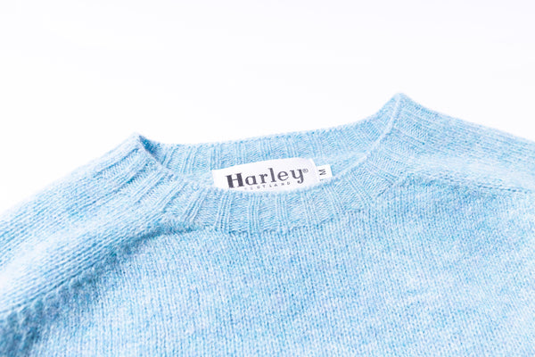 Close-up of a blue sweater with a Harley label on a white background