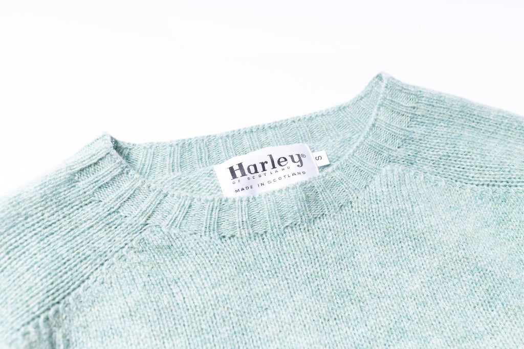 Close-up of a light blue sweater with a Harley label on a white background