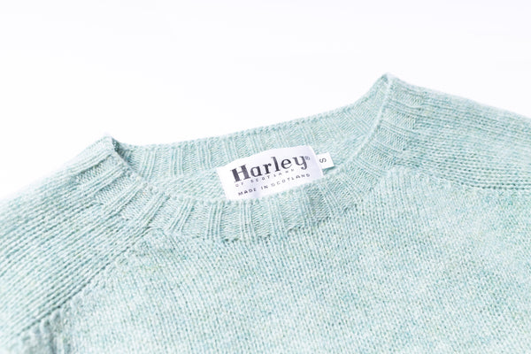 Close-up of a light blue sweater with a Harley label on a white background