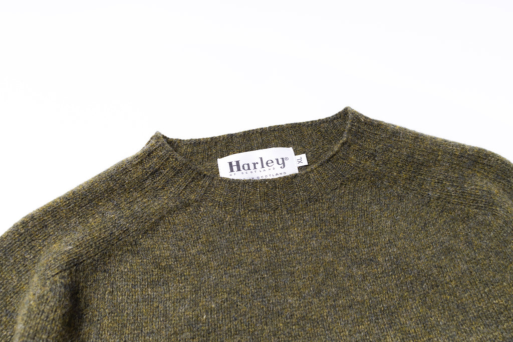 Close-up of a green sweater with a Harley label on a white background