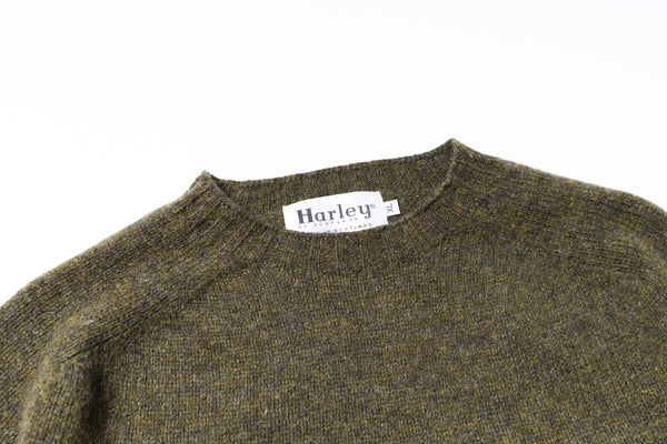 Close-up of a green sweater with a Harley label on a white background